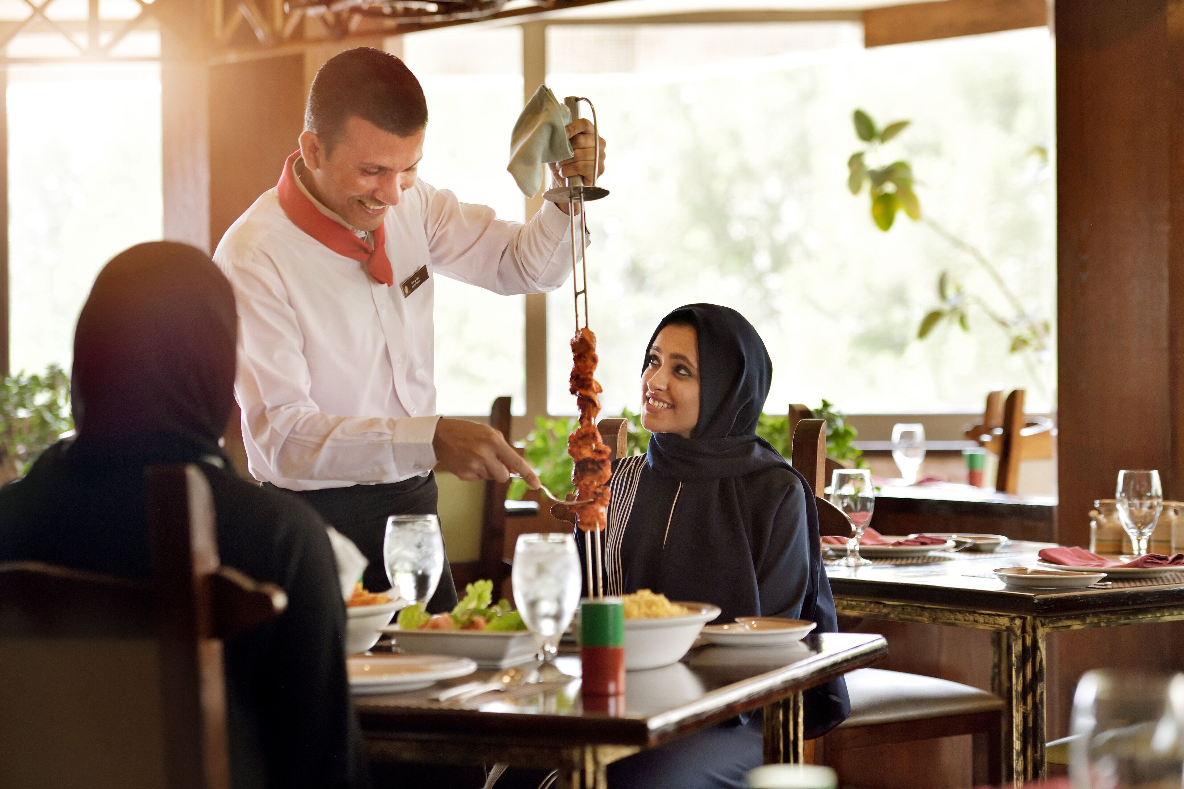A restaurant setting with a waiter serving food to a customer.