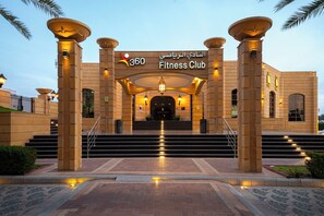 A building entrance with a sign reading "360 Fitness Club" and a staircase leading up to the entrance.
