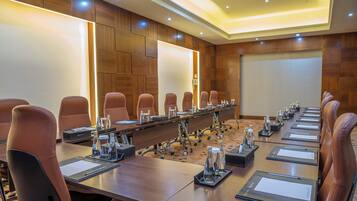 A conference room with a long table, brown leather chairs, and a whiteboard.
