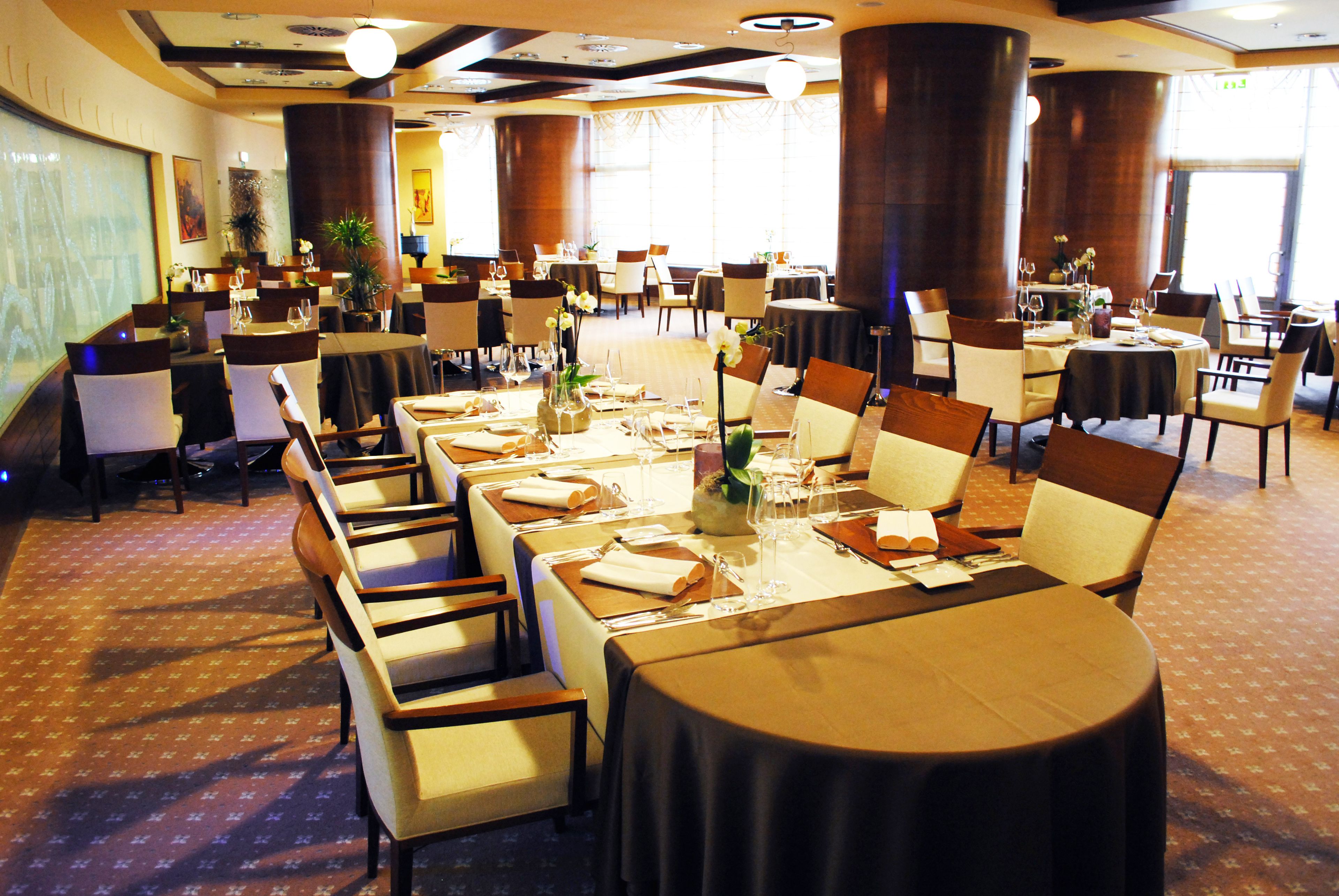 A banquet hall with round tables set for dining, surrounded by chairs.
