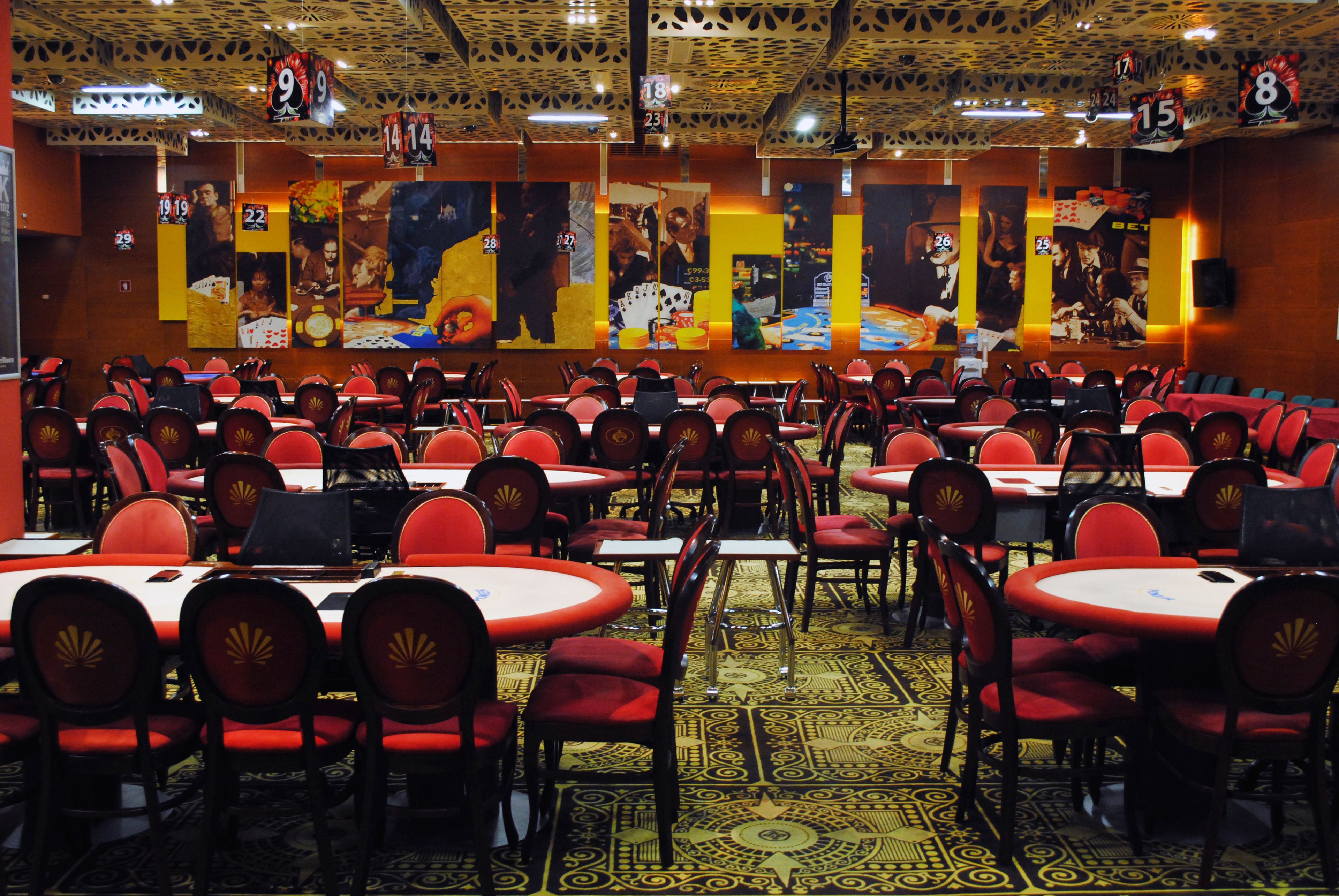 A casino with multiple blackjack tables and red chairs.