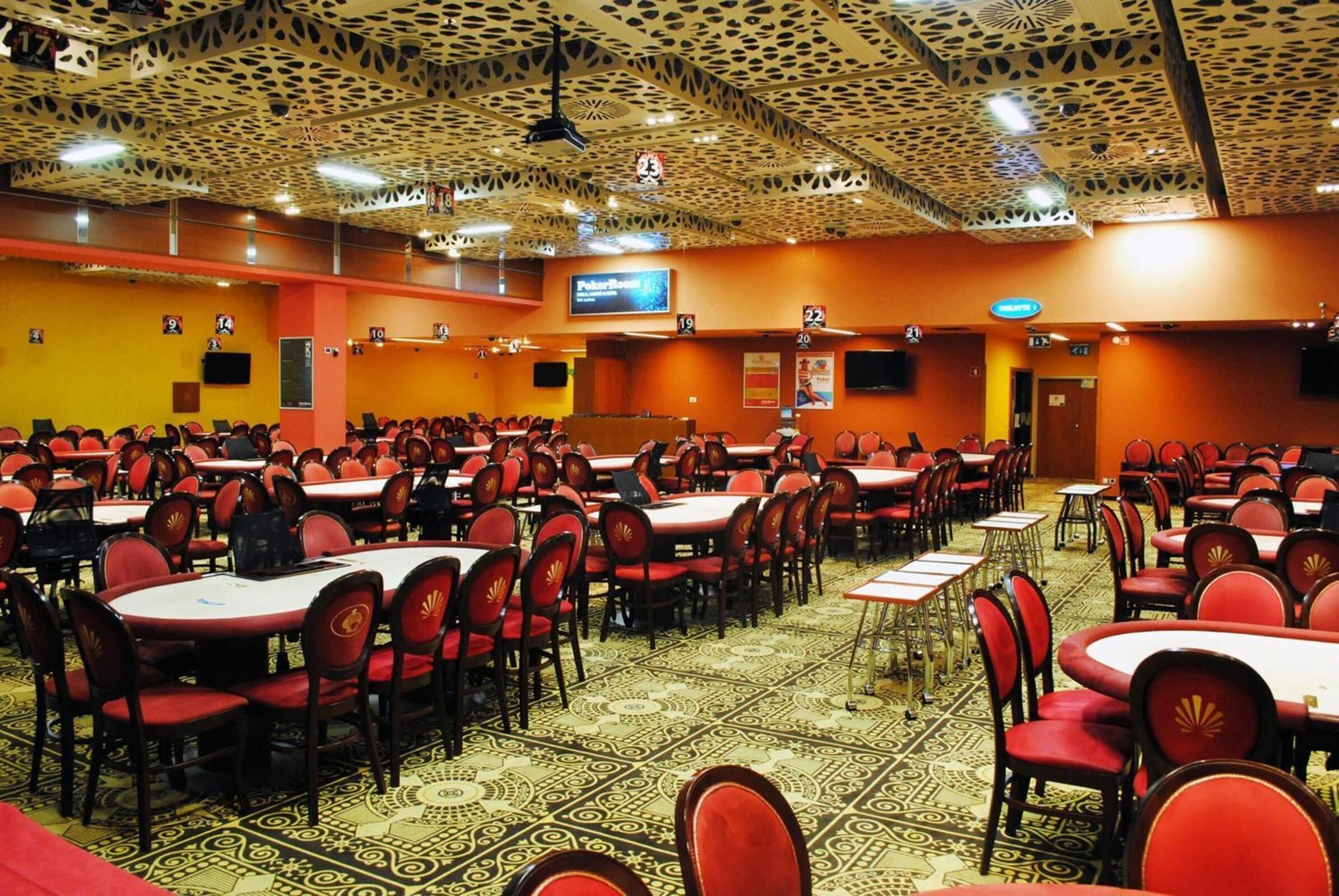 A large conference room with rows of tables and chairs, a patterned carpet, and a ceiling with a unique design.