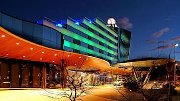 A modern hotel with a curved facade, large glass windows, and a prominent clock tower.