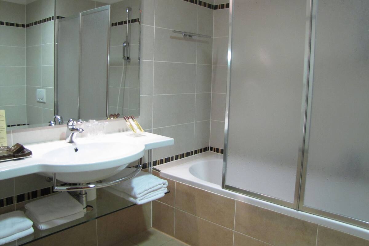 A bathroom with a sink, mirror, and shower.