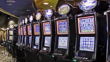 A row of slot machines with illuminated screens and various game themes.