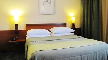 A hotel room with a bed, two bedside tables, a framed picture on the wall, and a curtain.