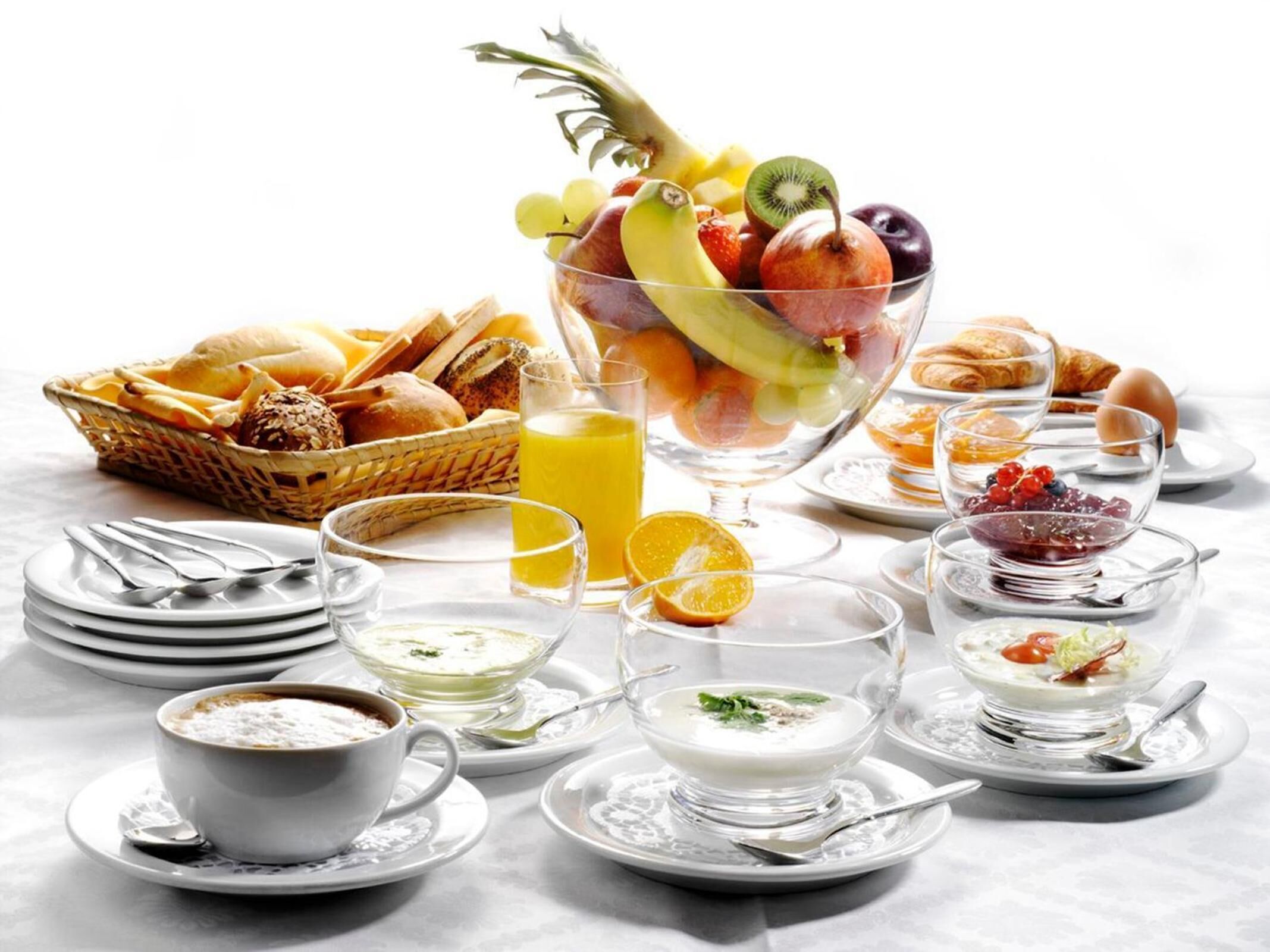 A breakfast buffet with various fruits, pastries, and beverages.