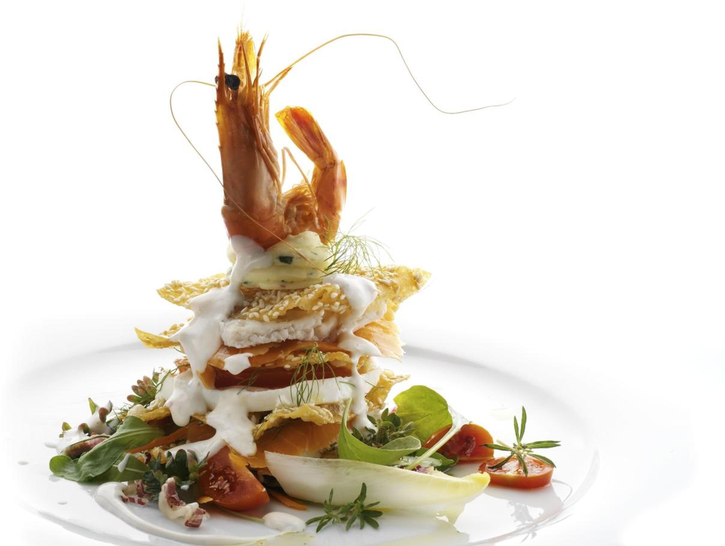 A seafood dish with a shrimp centerpiece, accompanied by various vegetables and a creamy sauce.