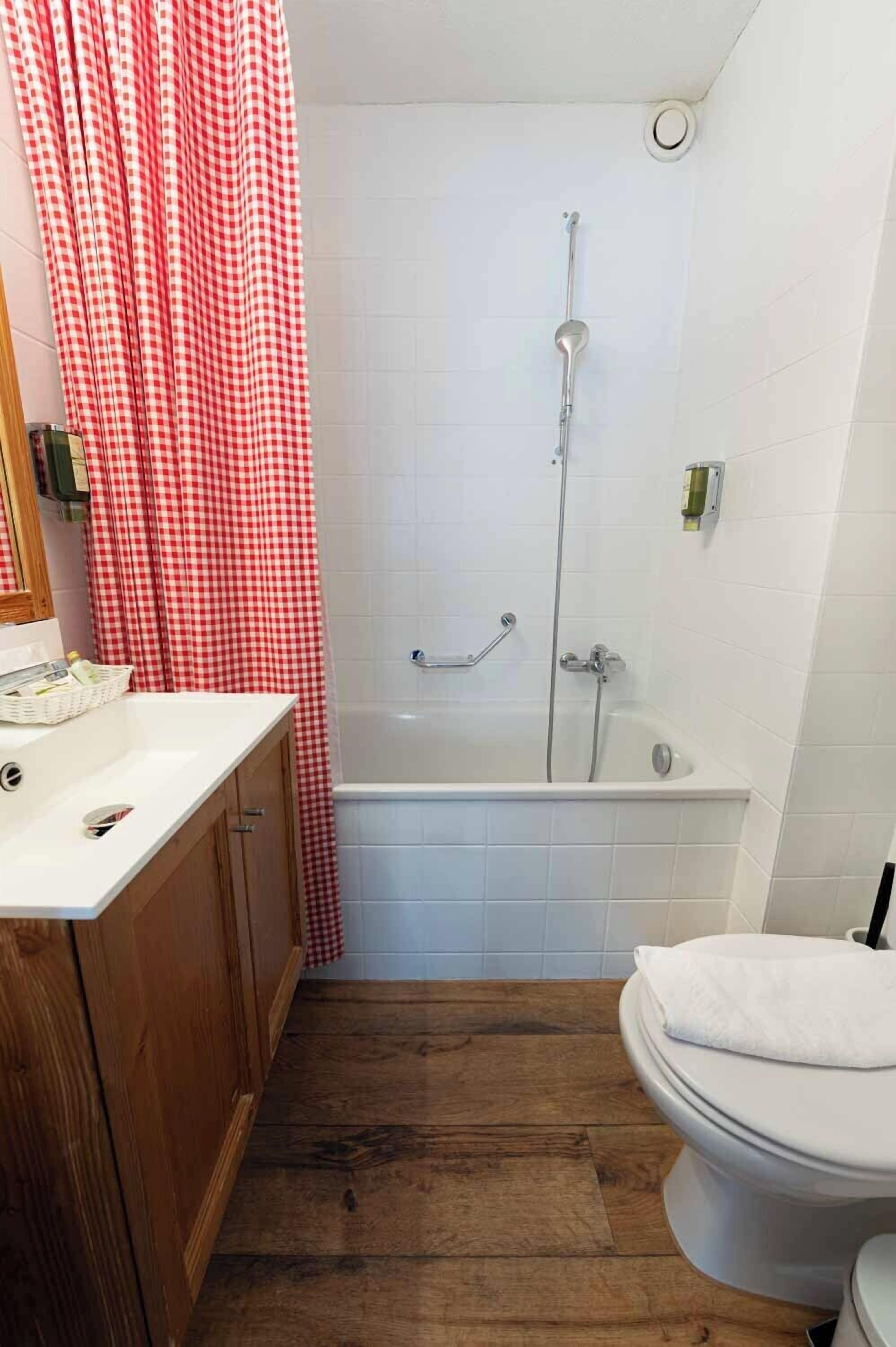 A bathroom with a wooden vanity, a white bathtub, and a shower with a glass door.
