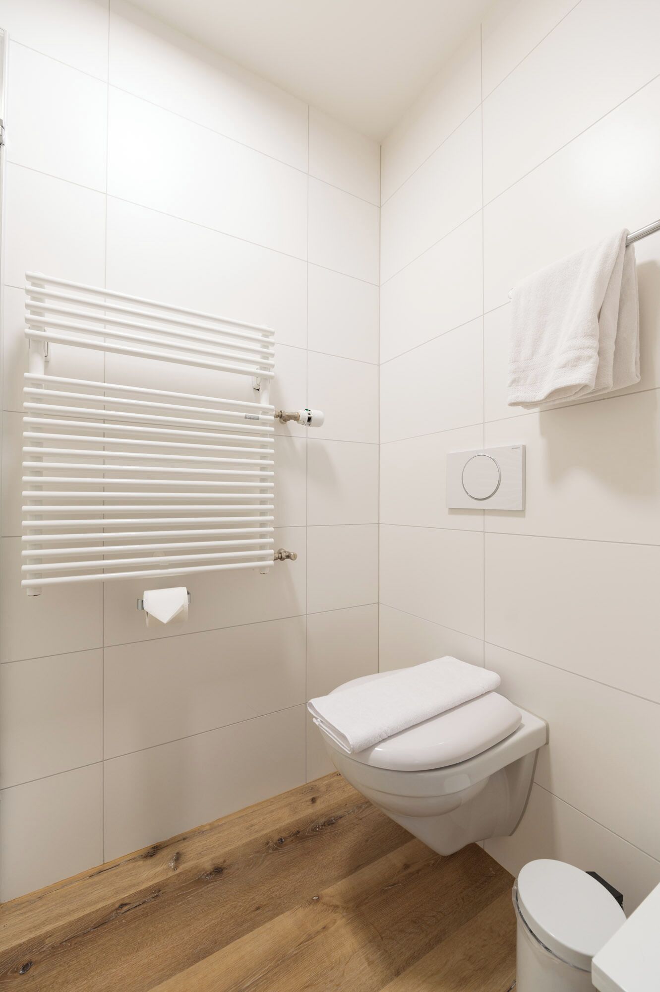 A bathroom with a toilet, a towel rack, and a radiator.