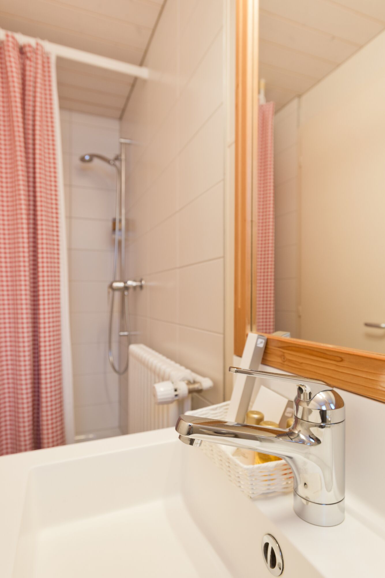A bathroom with a white sink, a chrome faucet, a shower with a glass door, and a mirror with a wooden frame.