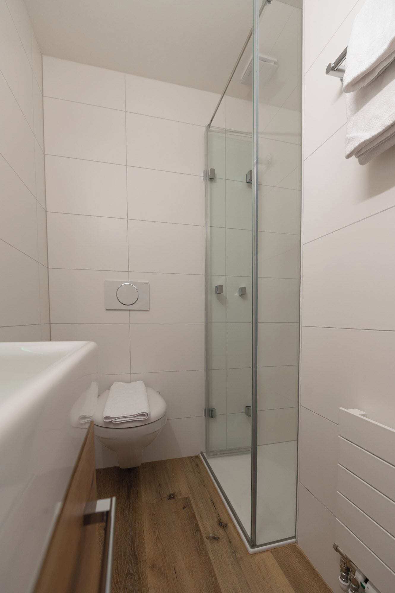 Une salle de bain moderne avec une douche à parois de verre, des toilettes et un lavabo équipé d’un porte-serviettes.