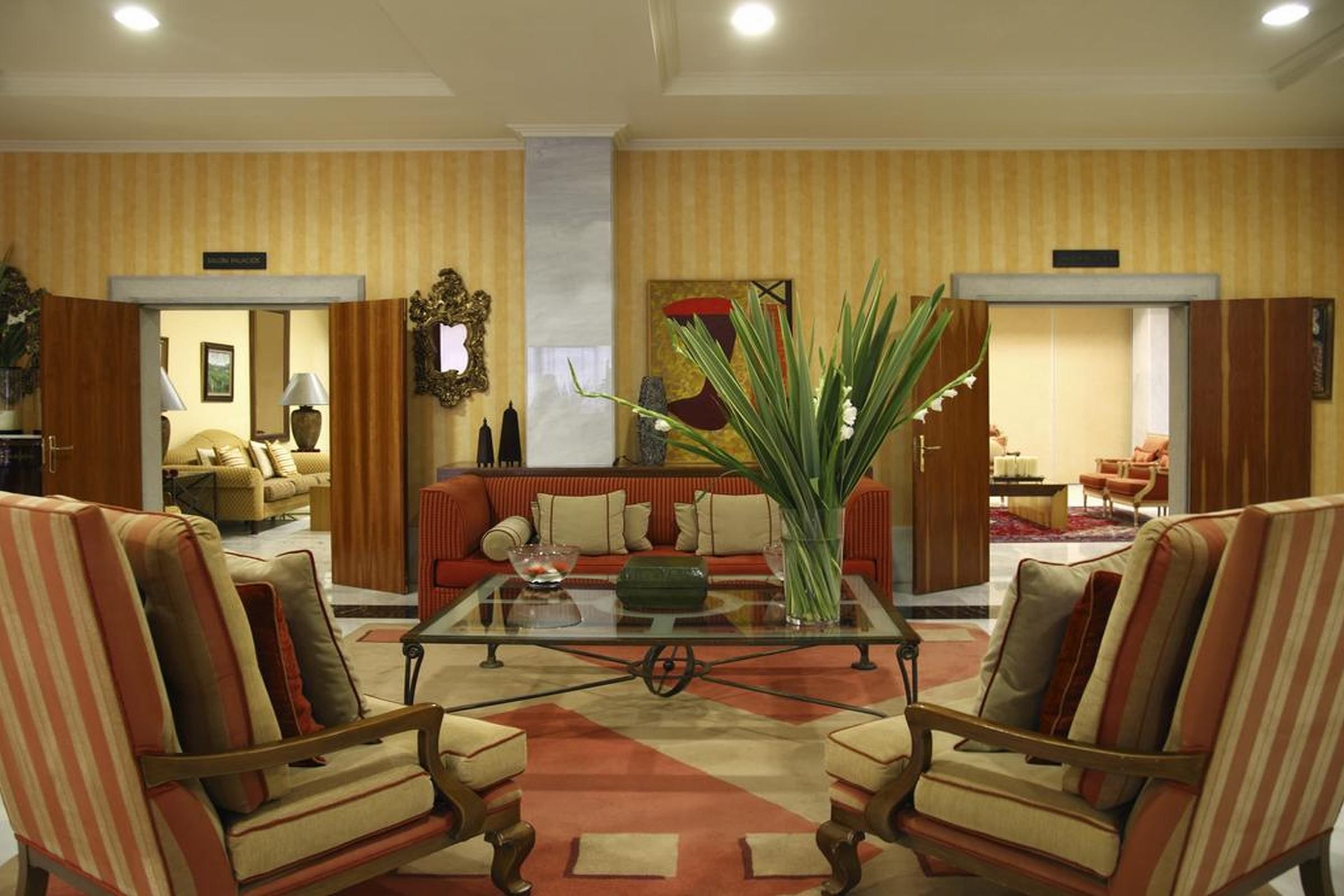 A hotel lobby with striped armchairs, a glass coffee table, and a sofa.