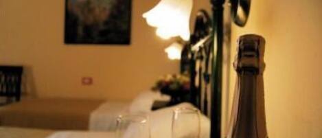 A hotel room with a bed, a nightstand, a lamp, a bottle of champagne, and a glass.