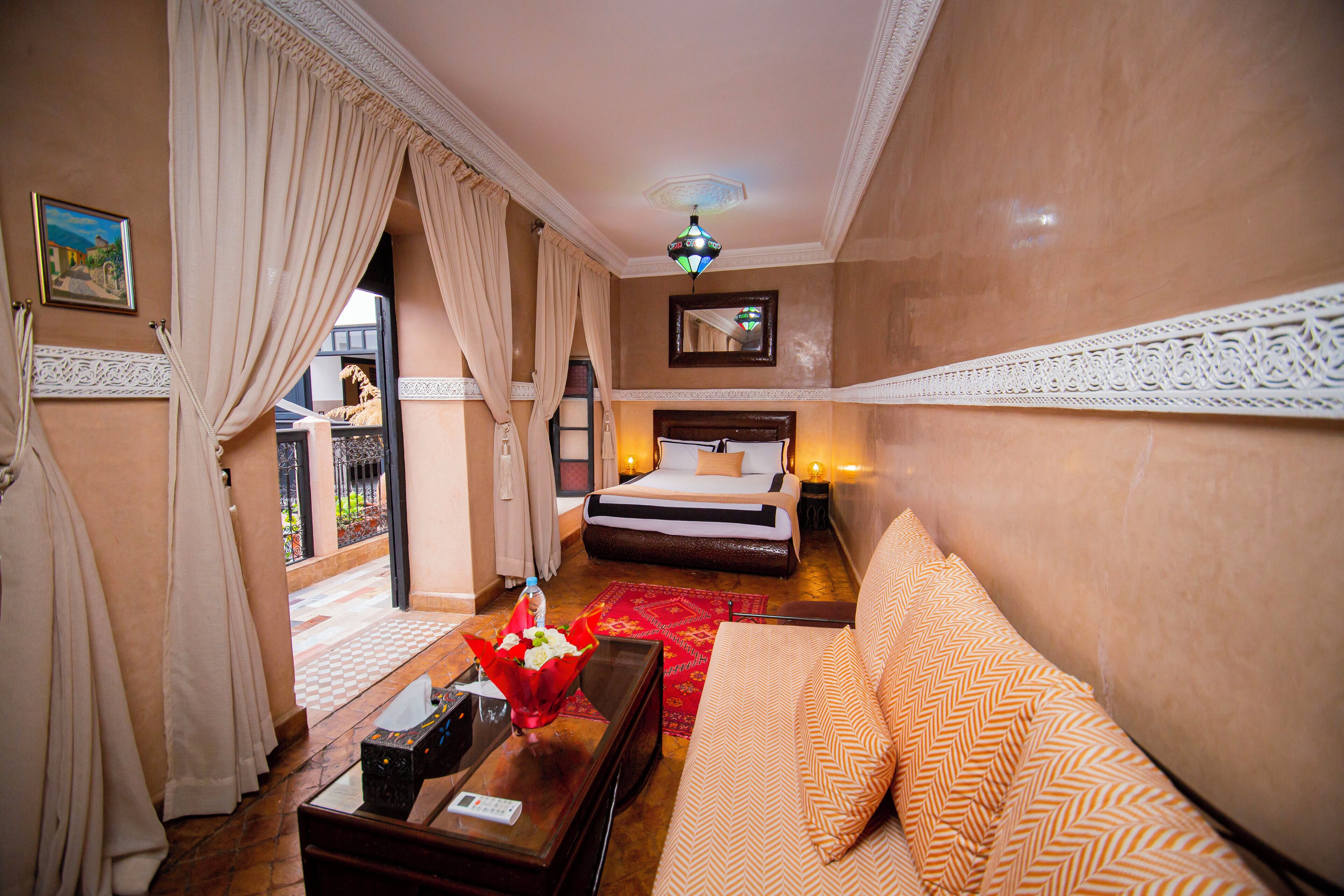 A hotel room with a bed, a sofa, a coffee table, and a view of the outside.