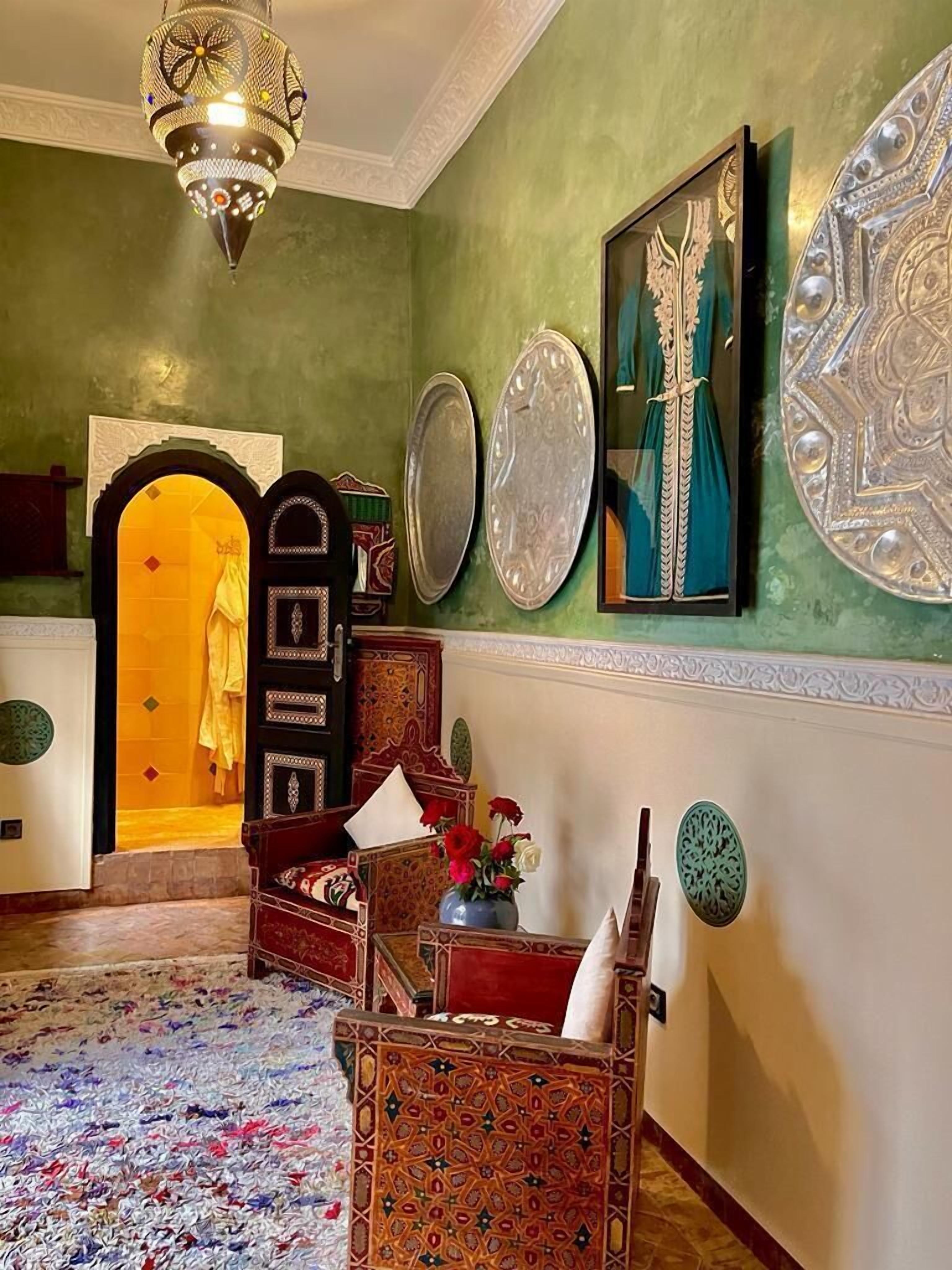A traditional interior with a patterned carpet, a chandelier, and decorative wall art.