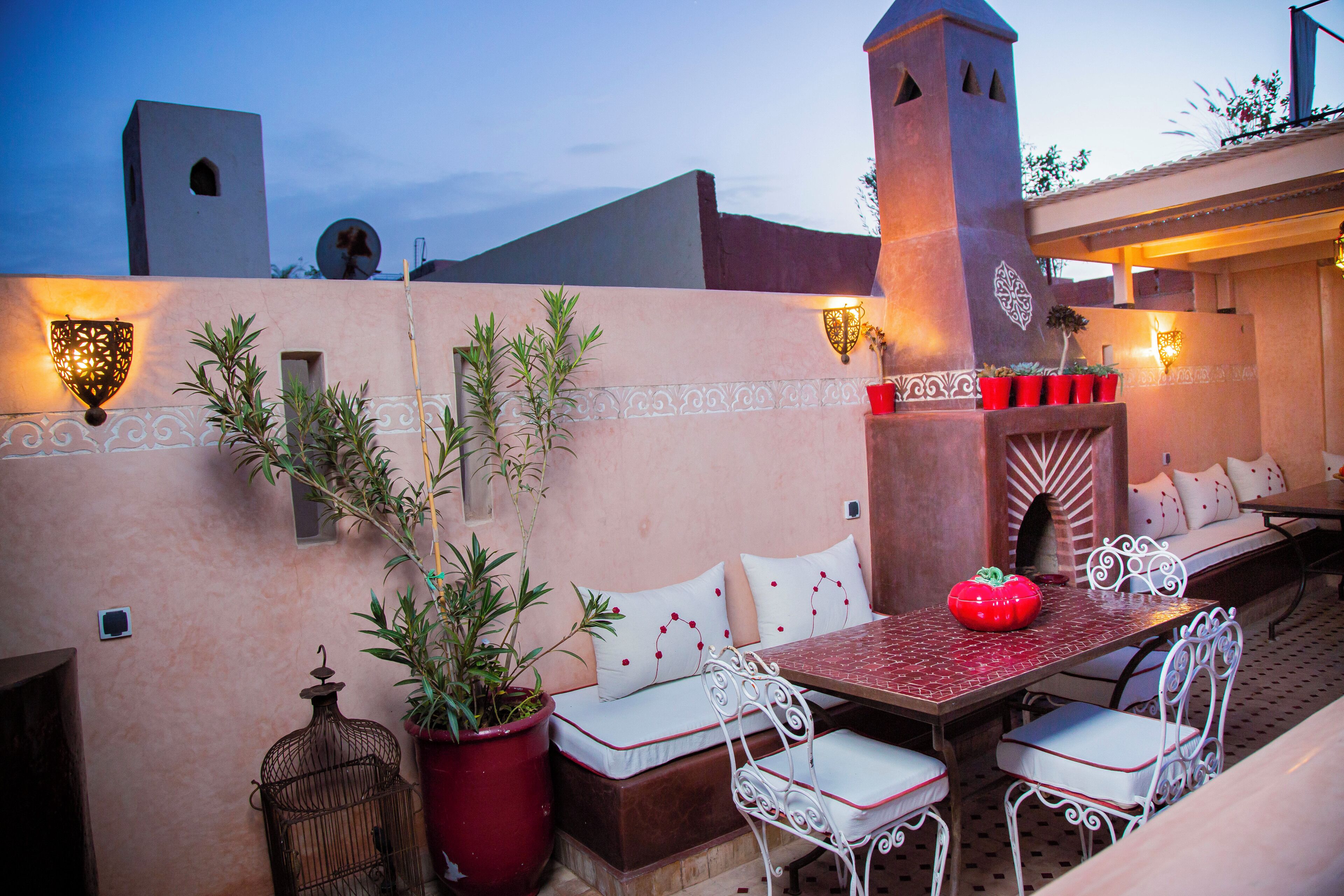 An outdoor patio with a table and chairs, a red decorative object, and potted plants.