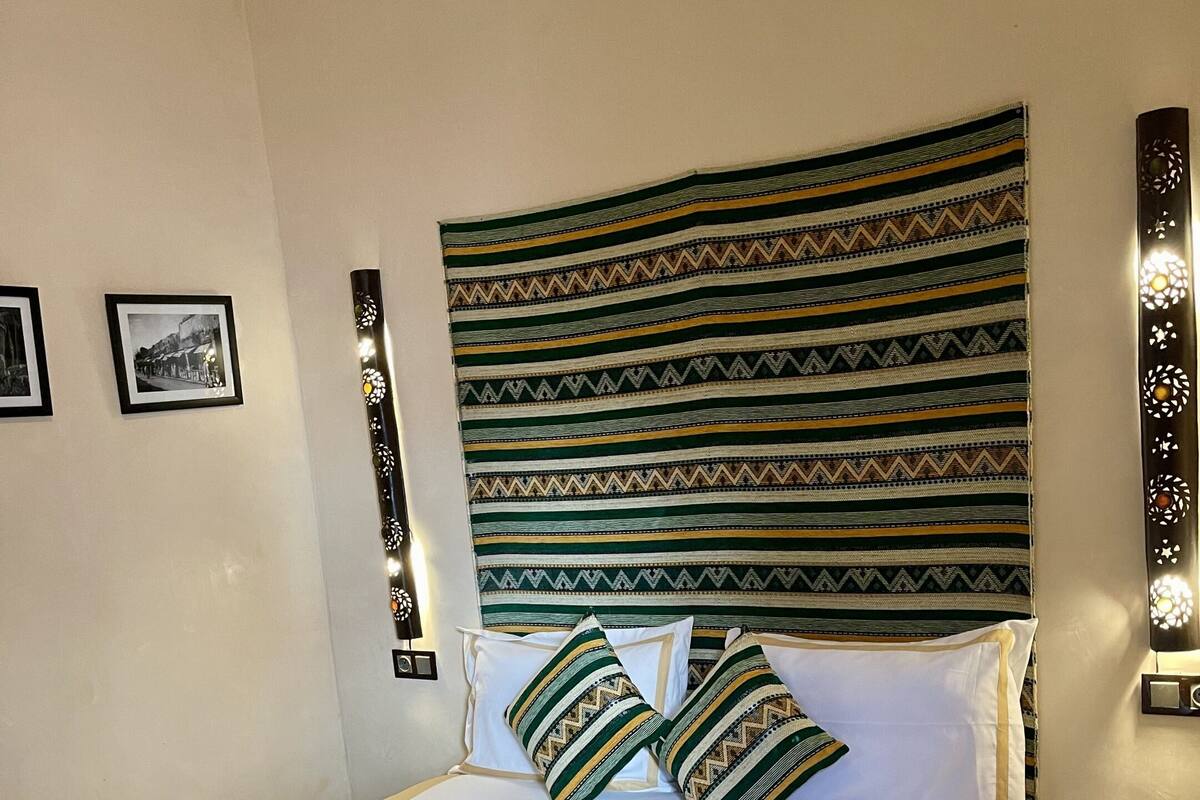 Una habitación de hotel con una cama grande, cabecera estampada y almohadas.