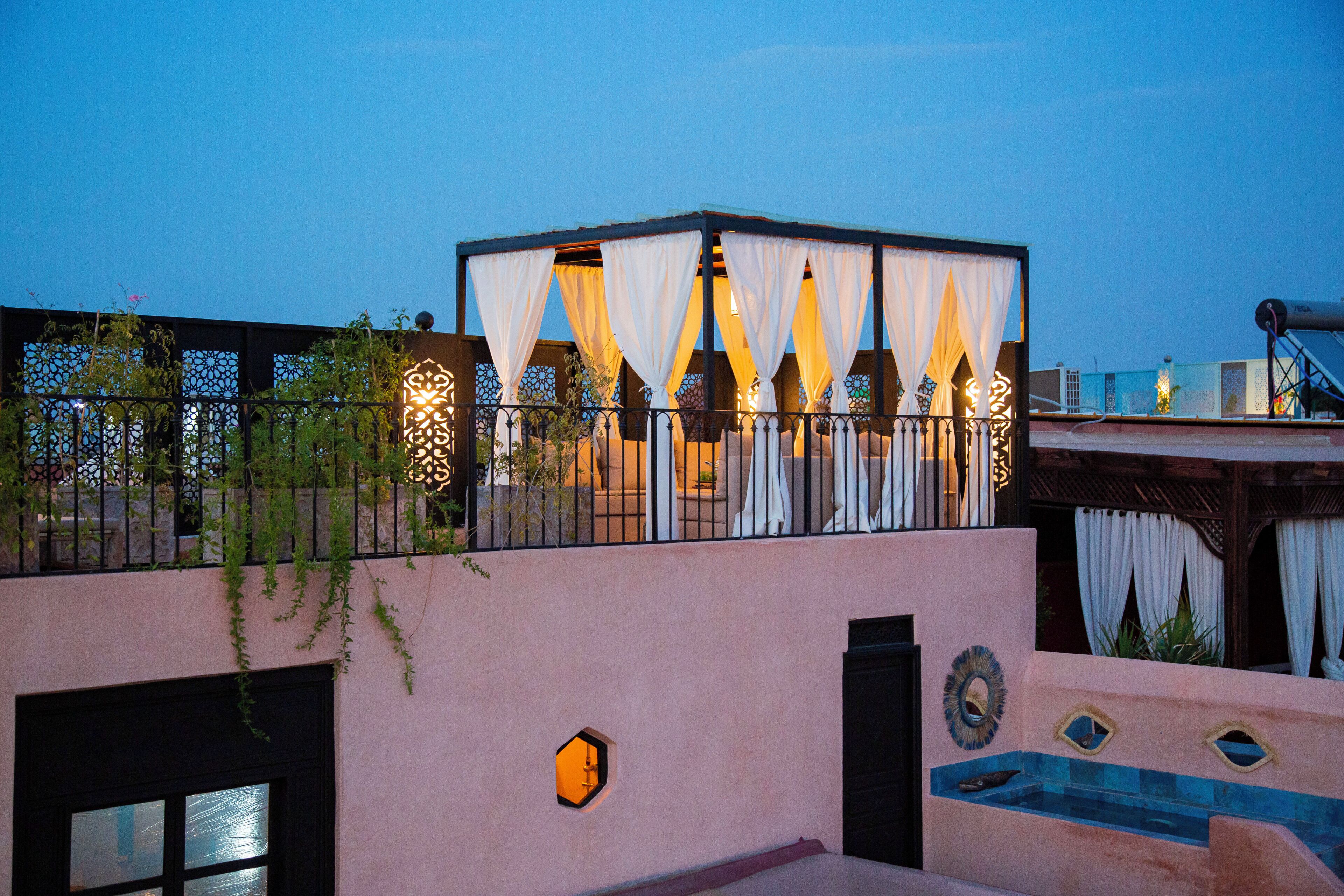 Una terrazza panoramica con zona salotto coperta, piscina e parete decorativa.