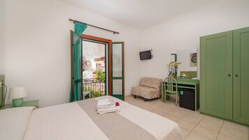 Habitación de hotel con cama, escritorio, silla, televisor y armario.