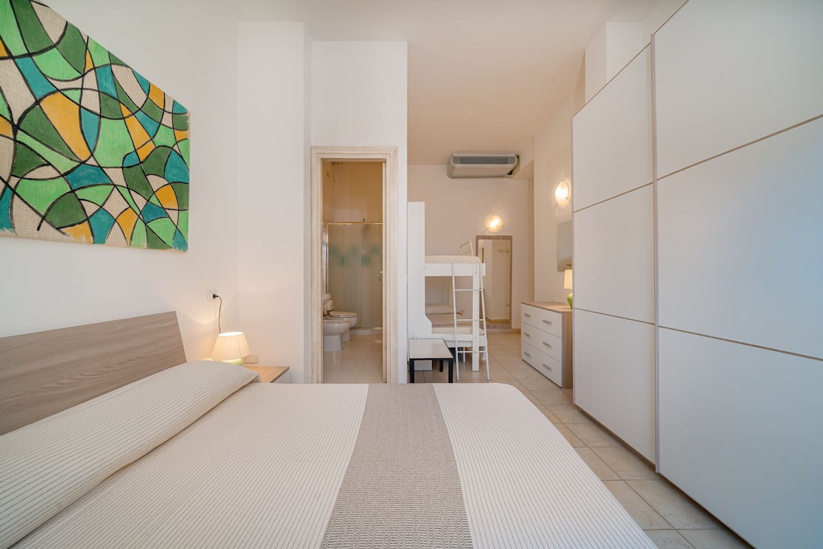 A modern bedroom with a bed, bedside table, and a wardrobe.