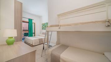 Une chambre d’hôtel compacte avec un lit superposé, un bureau avec une lampe et une vue sur le balcon extérieur.