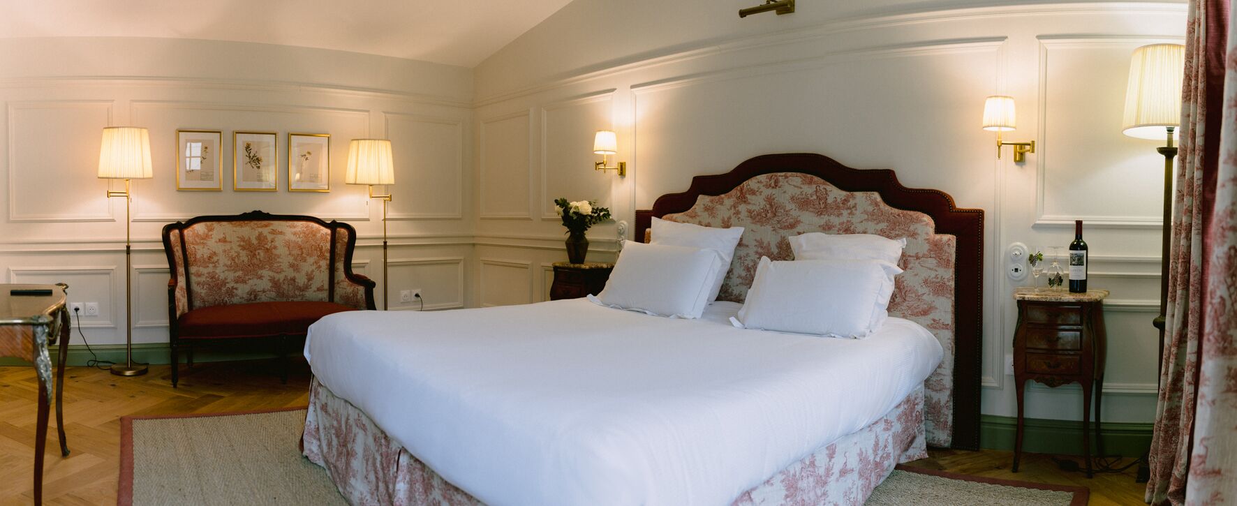 A neatly arranged hotel room with a large bed, a chair, and two bedside tables with lamps.