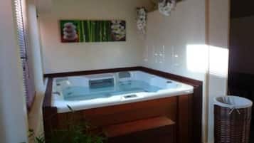 Un cuarto de spa con un jacuzzi, escalones de madera, un bote de basura y decoración mural.