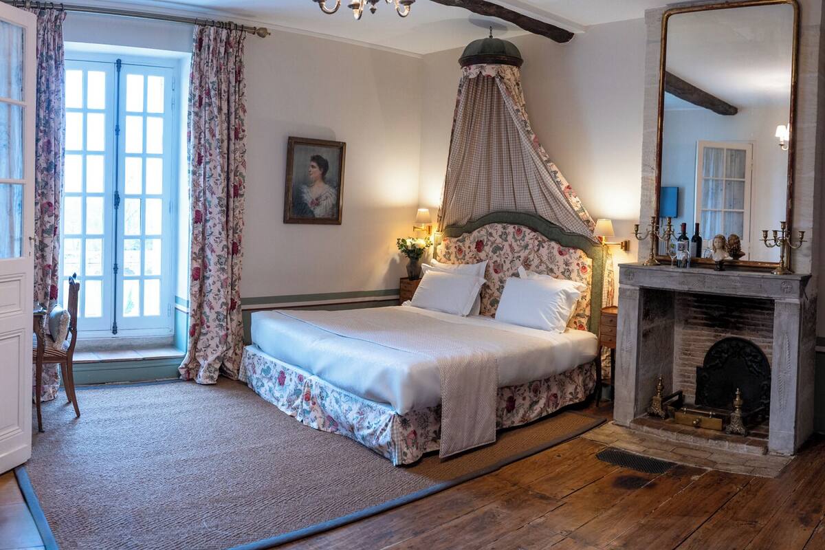 Un dormitorio con una cama con dosel, una chimenea y un espejo grande.