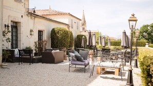 Un patio con mobiliario exterior, una iglesia y un seto bien cuidado.