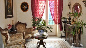 Um quarto com uma janela grande, um vaso de planta, uma cadeira, uma mesa e um armário.