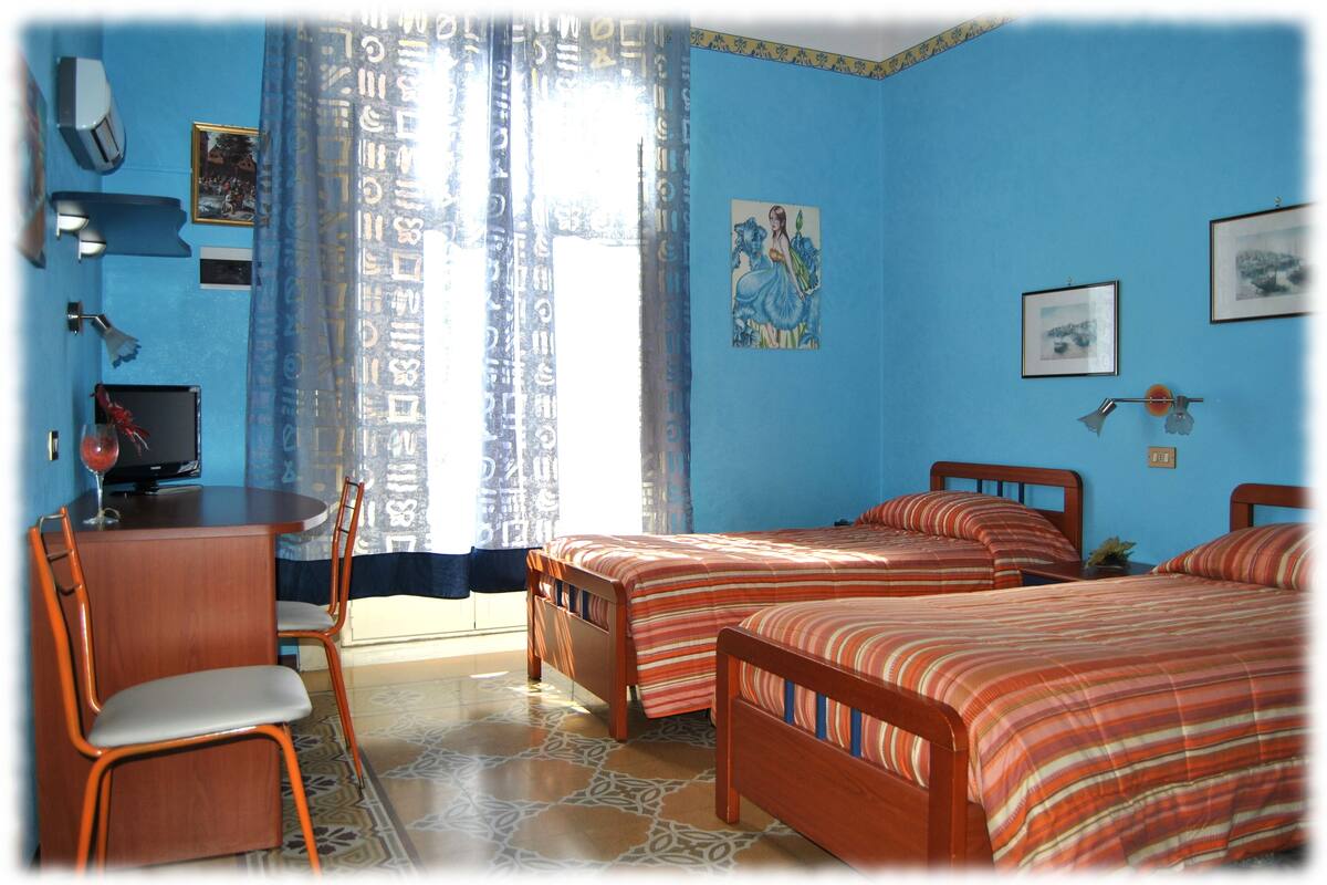A room with two beds, a desk, a chair, and a television.