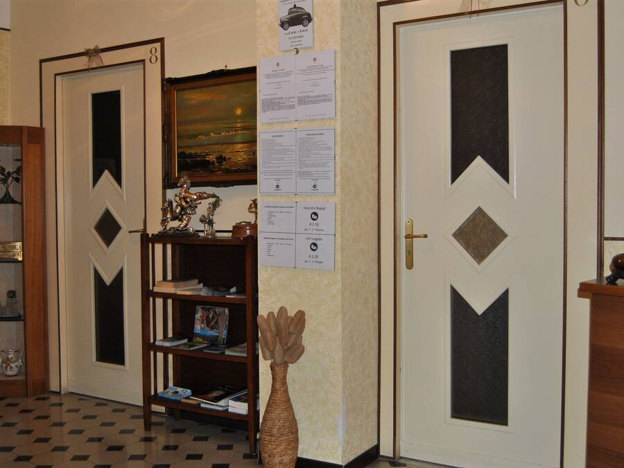 Un pasillo con dos puertas, una estantería y un jarrón decorativo.