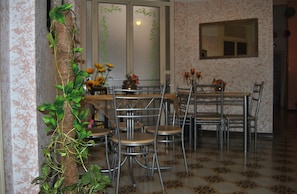 A dining area with metal chairs and a table, surrounded by patterned wallpaper and a plant. - Bed and Breakfast D'Angelo (Palermo)