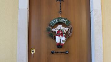 A wooden door with a 'WELCOME' sign and a small bear decoration.