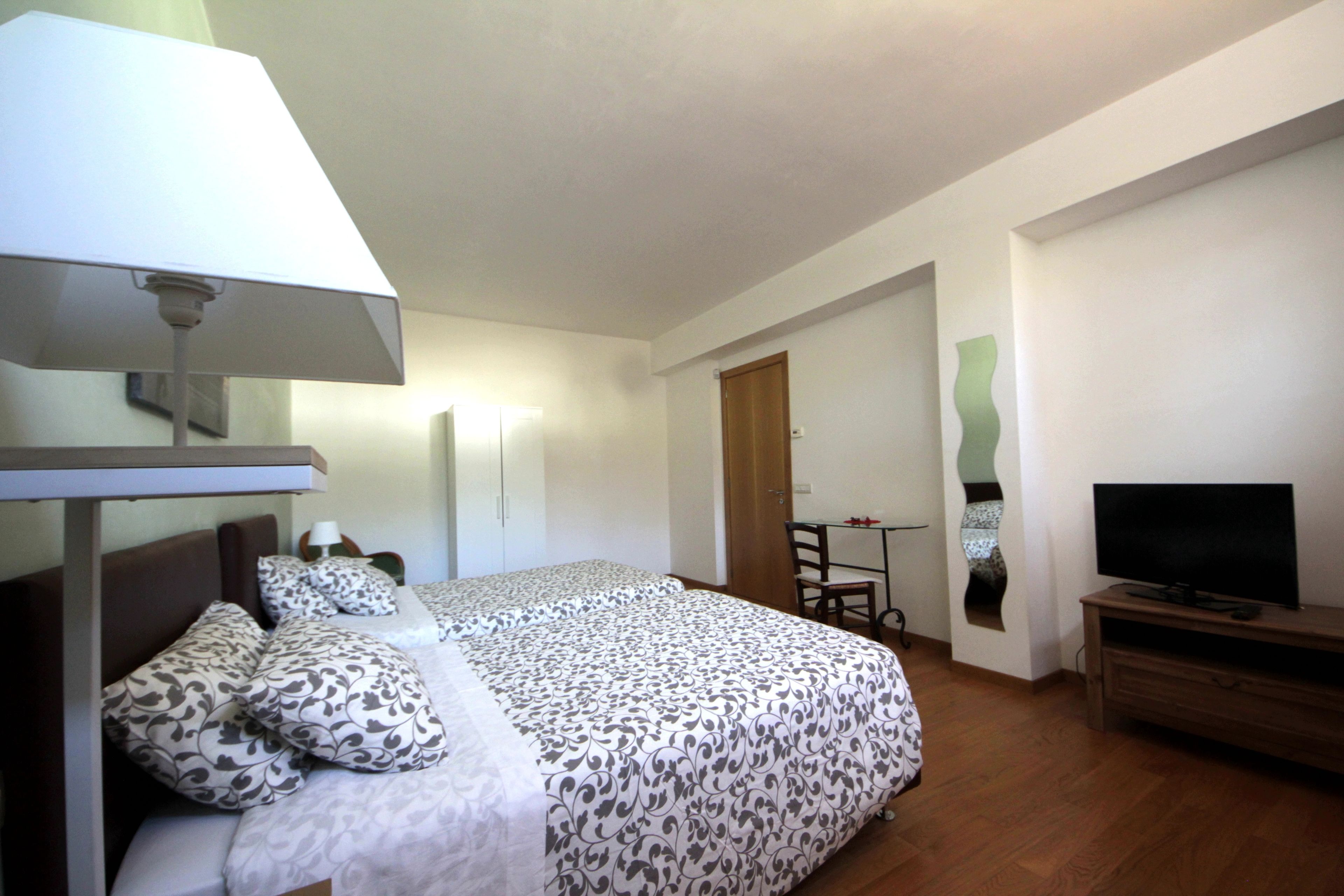 A hotel room with a bed, a TV, a desk, and a chair.
