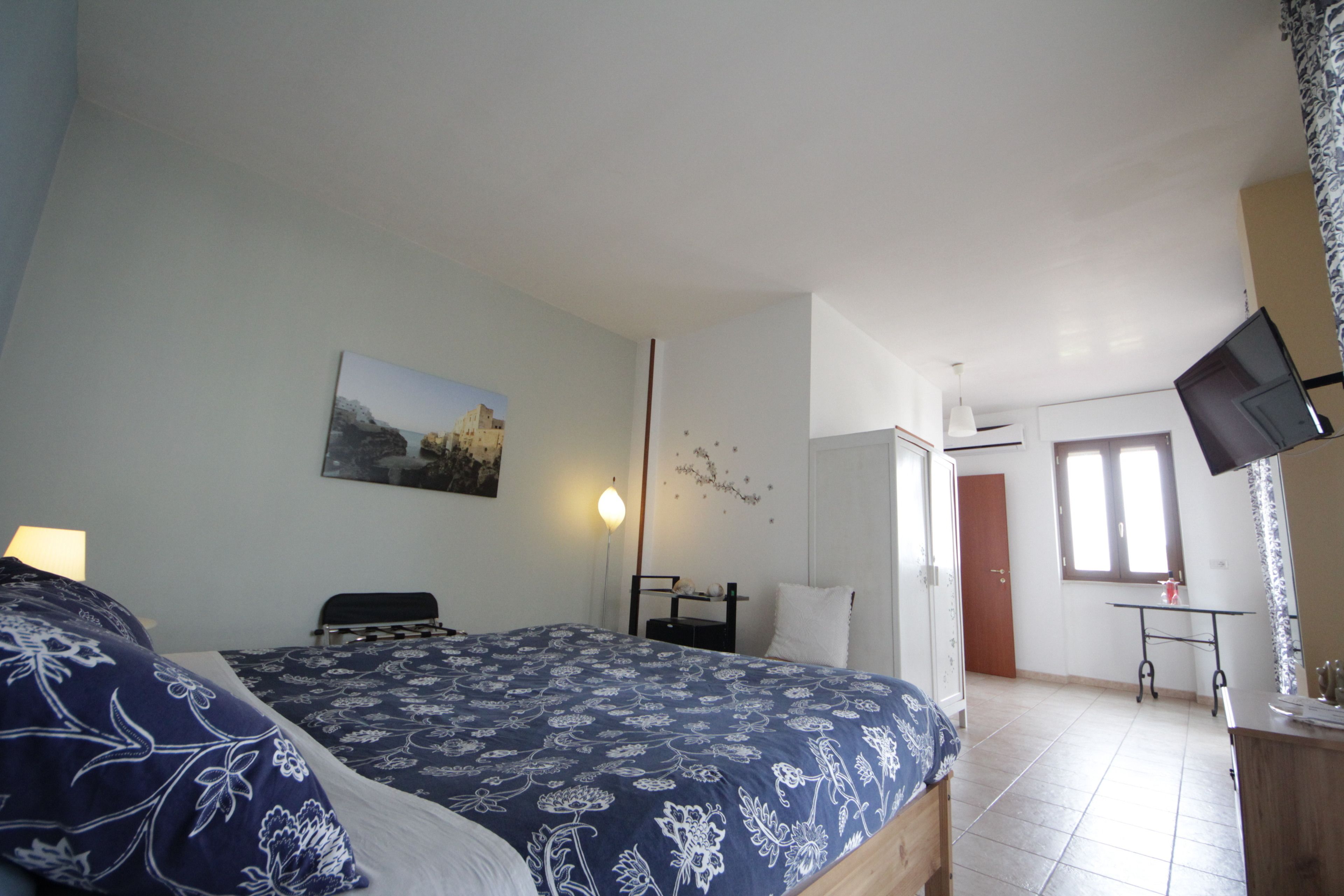 Una camera da letto con un letto, un comodino, una lampada e un televisore montato a parete.