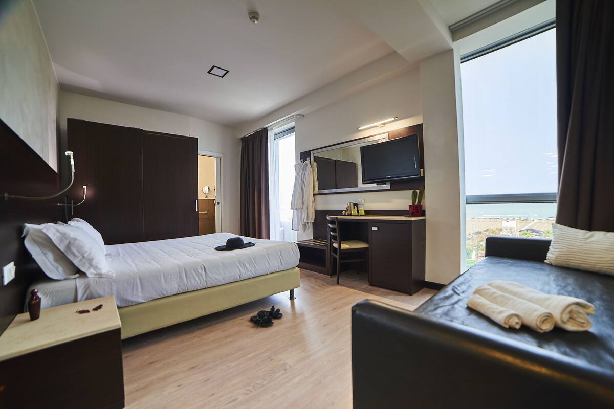 A hotel room with a bed, desk, and a TV.