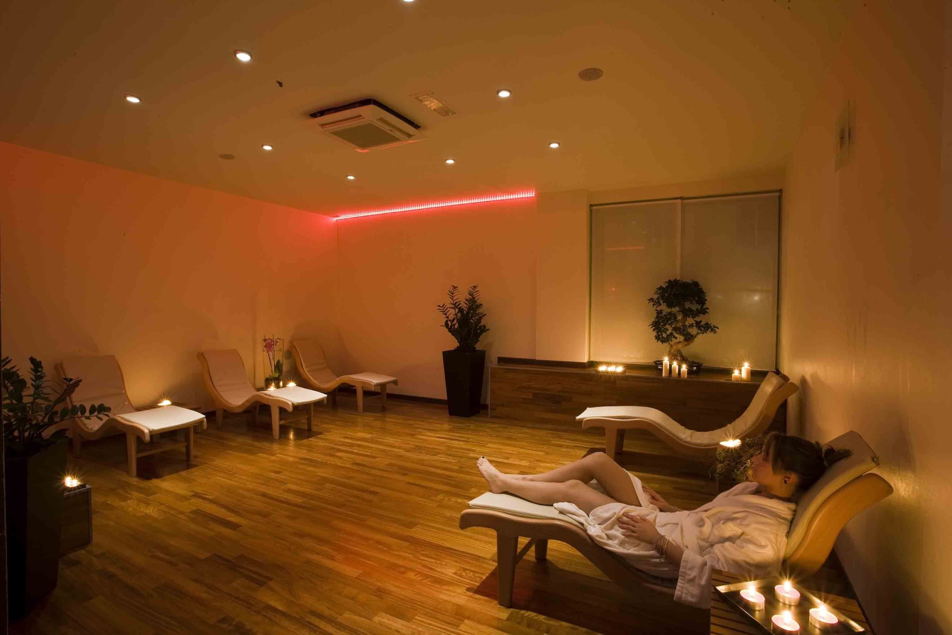 Un cuarto de spa con piso de madera, varias sillas de masaje y un ventanal grande.
