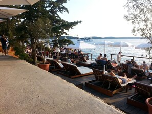 An outdoor seating area with lounge chairs and umbrellas overlooking the sea. - Guesthouse Tea Hvar (Hvar)