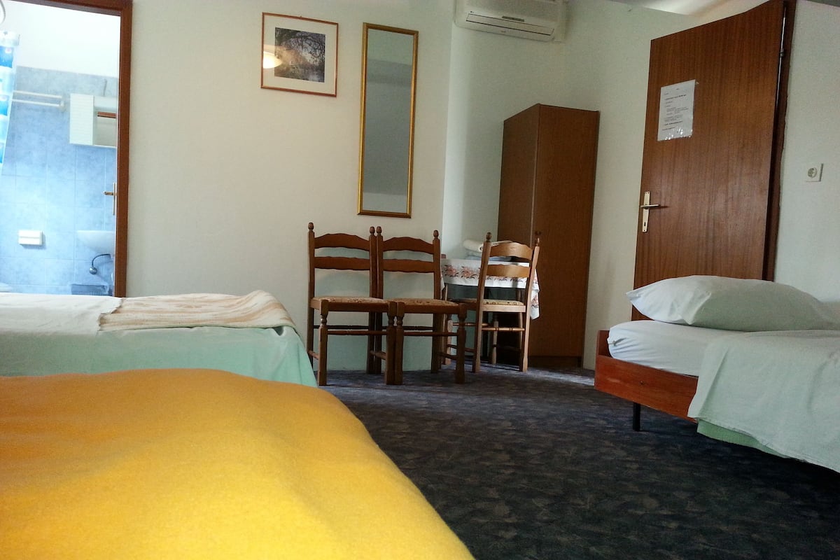 Habitación de hotel con dos camas, una silla de madera, un escritorio y un armario.