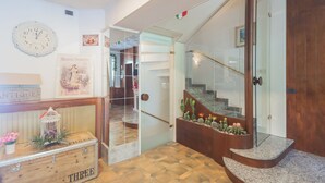 A modern interior with a wooden staircase, a glass door leading to a hallway, and a decorative cactus planter. - Hotel Mirabeau (Bellagio)