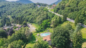 A mountainous landscape with a swimming pool, lounge chairs, and a path leading to a building. - Hotel Mirabeau (Bellagio)