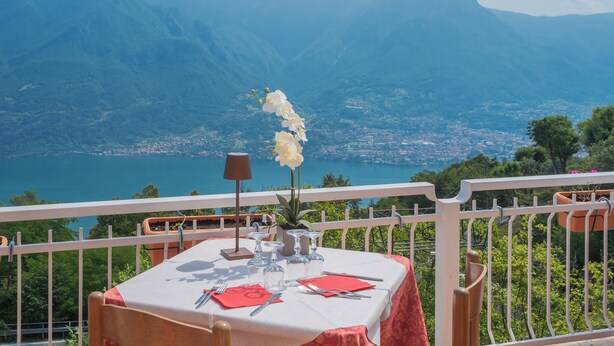 A table set for dining with a mountain view, a potted plant, and a lamp. - Hotel Mirabeau (Bellagio)