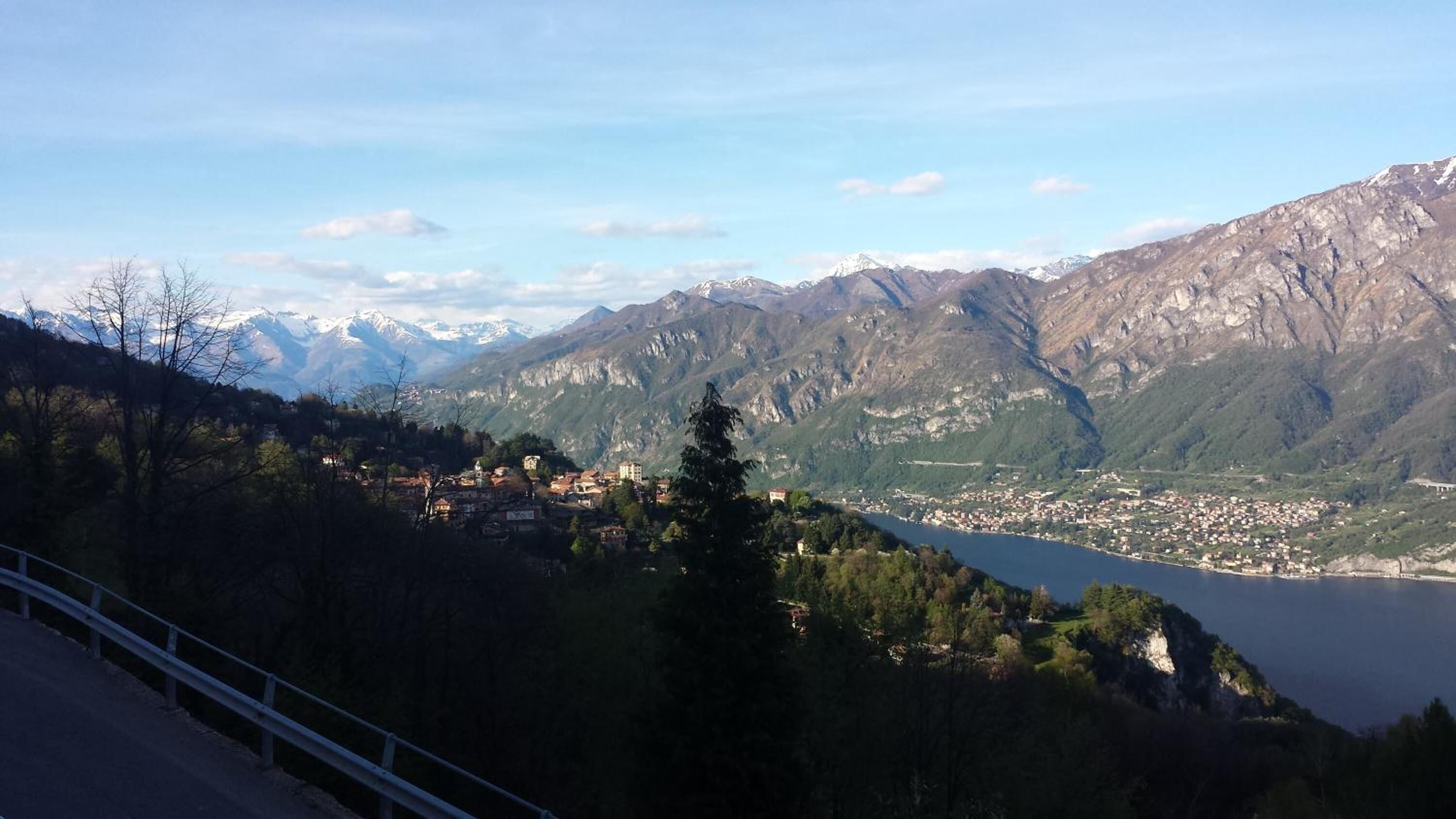 A mountainous landscape with a town nestled at the base, overlooking a lake.