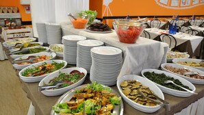 A buffet table with various food items and stacked plates.