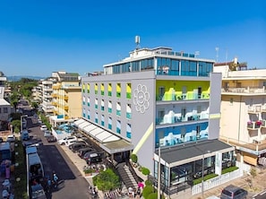 A multi-story hotel with a modern design, featuring balconies and a central atrium.