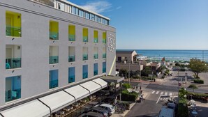 A hotel with a modern facade, large windows, and a view of the beach.