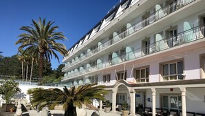 A multi-story hotel with balconies, a courtyard with seating, and palm trees. - Nuevo Vichona (Sanxenxo)