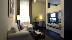 A modern hotel room with a sofa, armchair, coffee table, desk, and TV. - Romeo al Babuino (Rome)